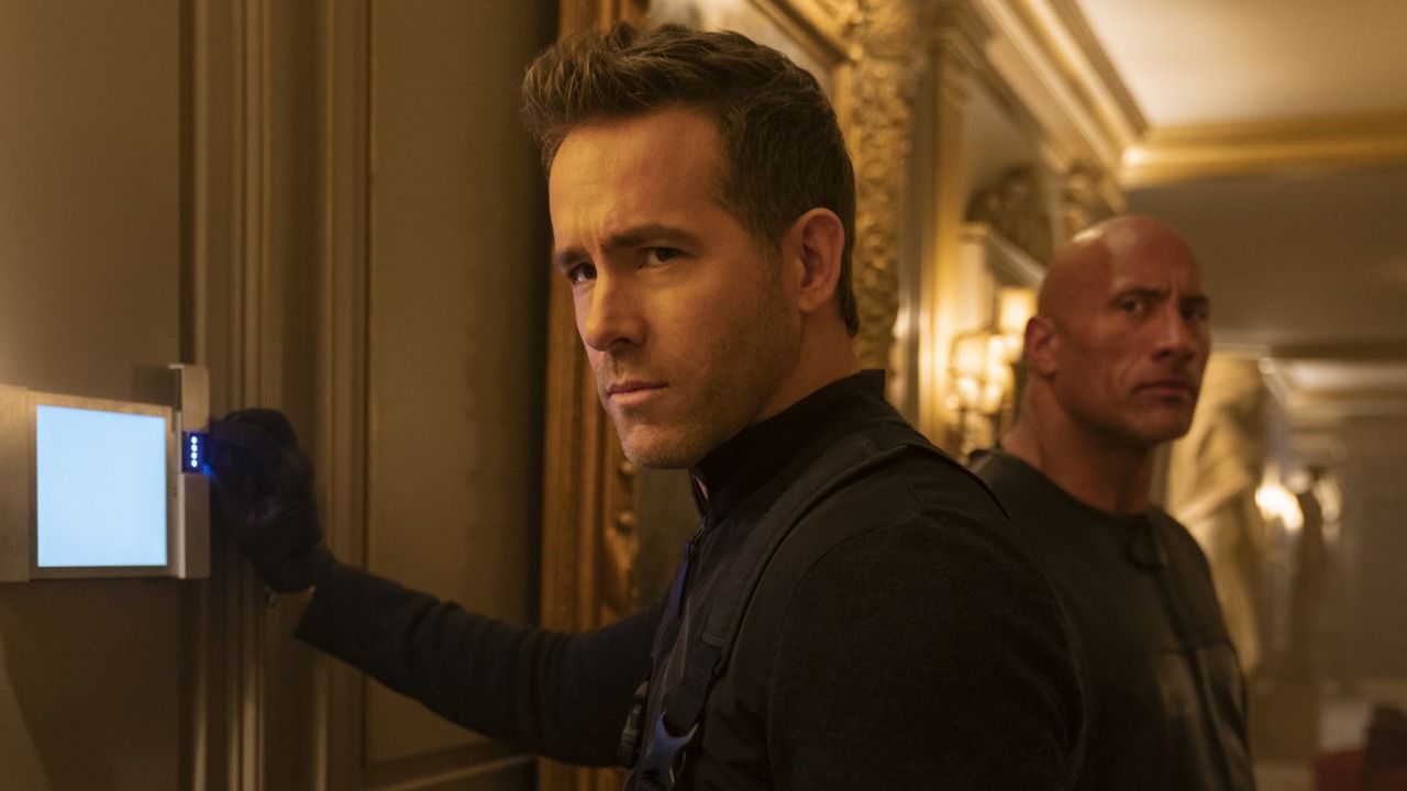 Ryan Reynolds in a hallway and The Rock behind him in Red Notice