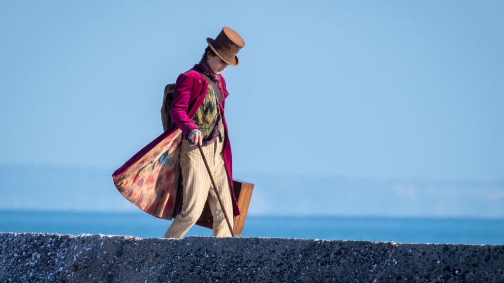 Man with top hat and cane walks along the coast