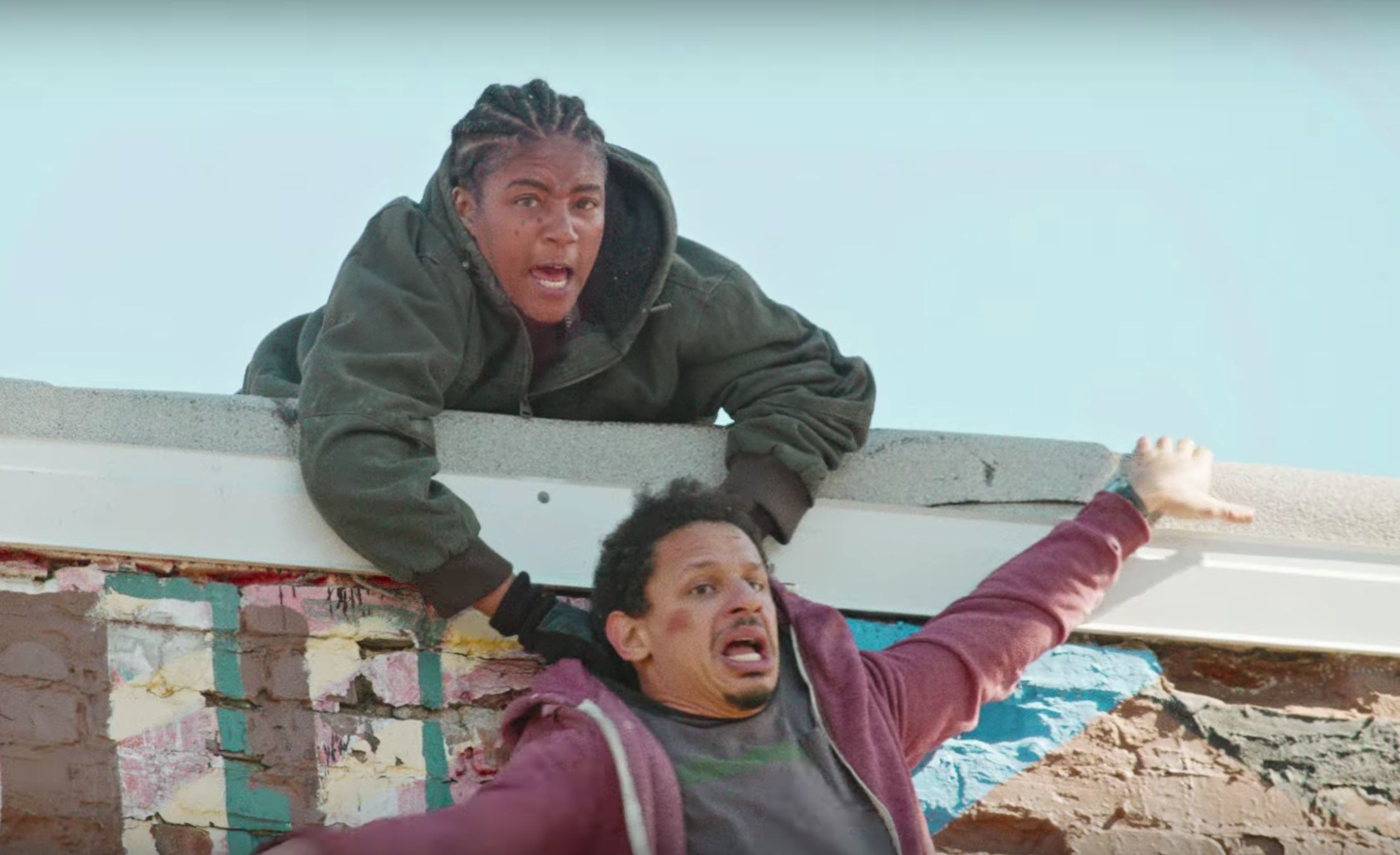 Girl holds guy as he flails and falls over edge of building