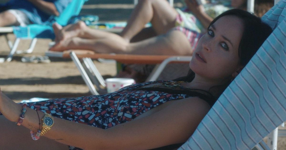 Dakota Johnson reclines on the beach in The Lost Daughter