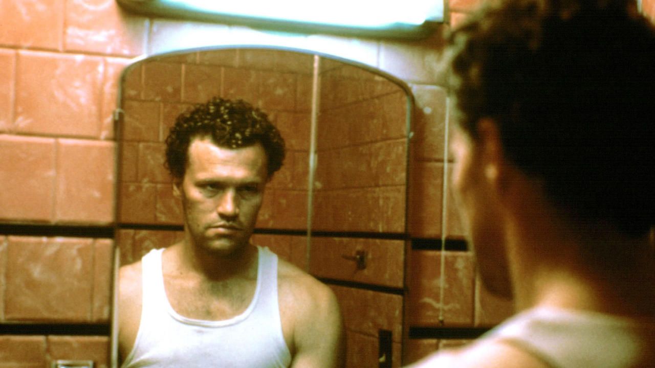 Michael Rooker looks in a mirror in Henry: Portrait of a Serial Killer
