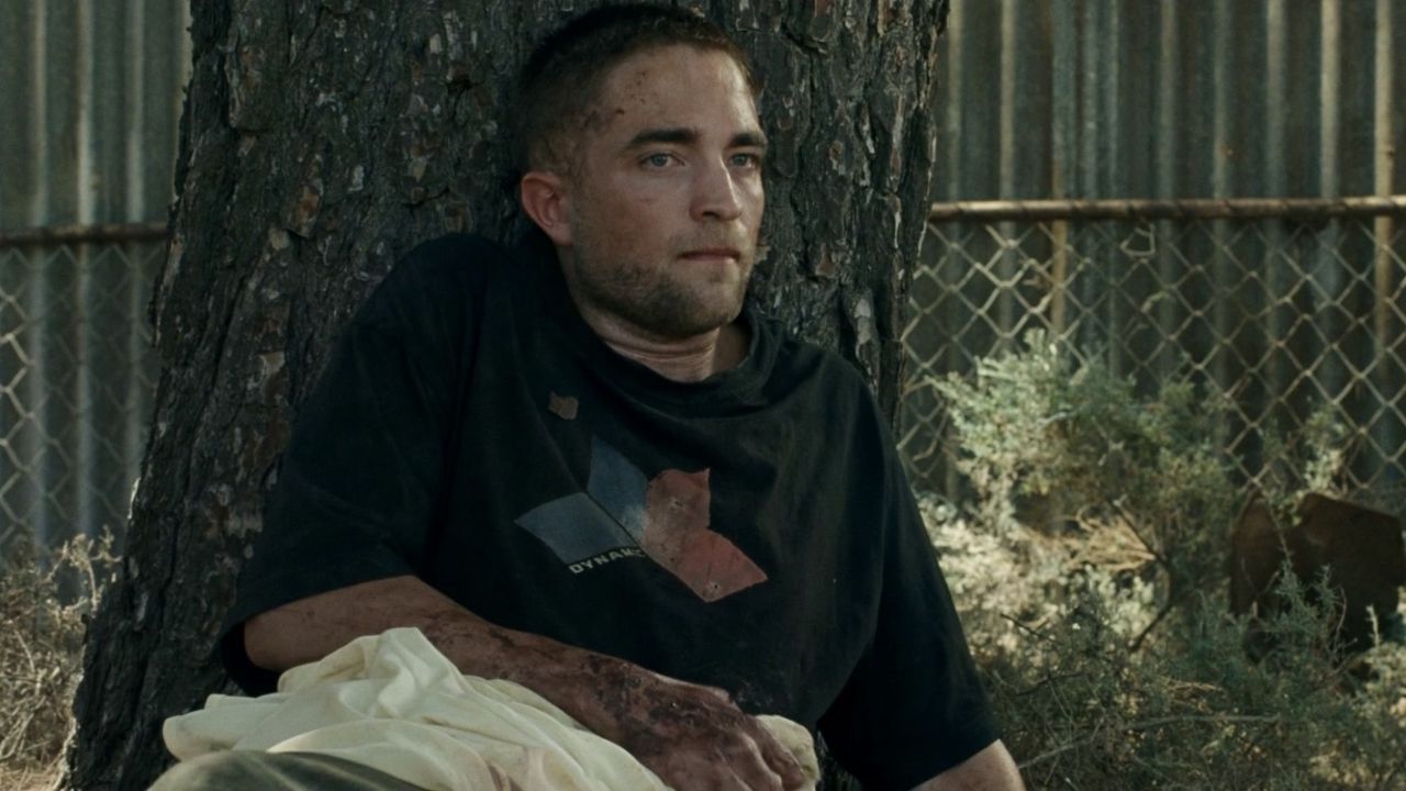Robert Pattinson sits against a tree in The Rover.