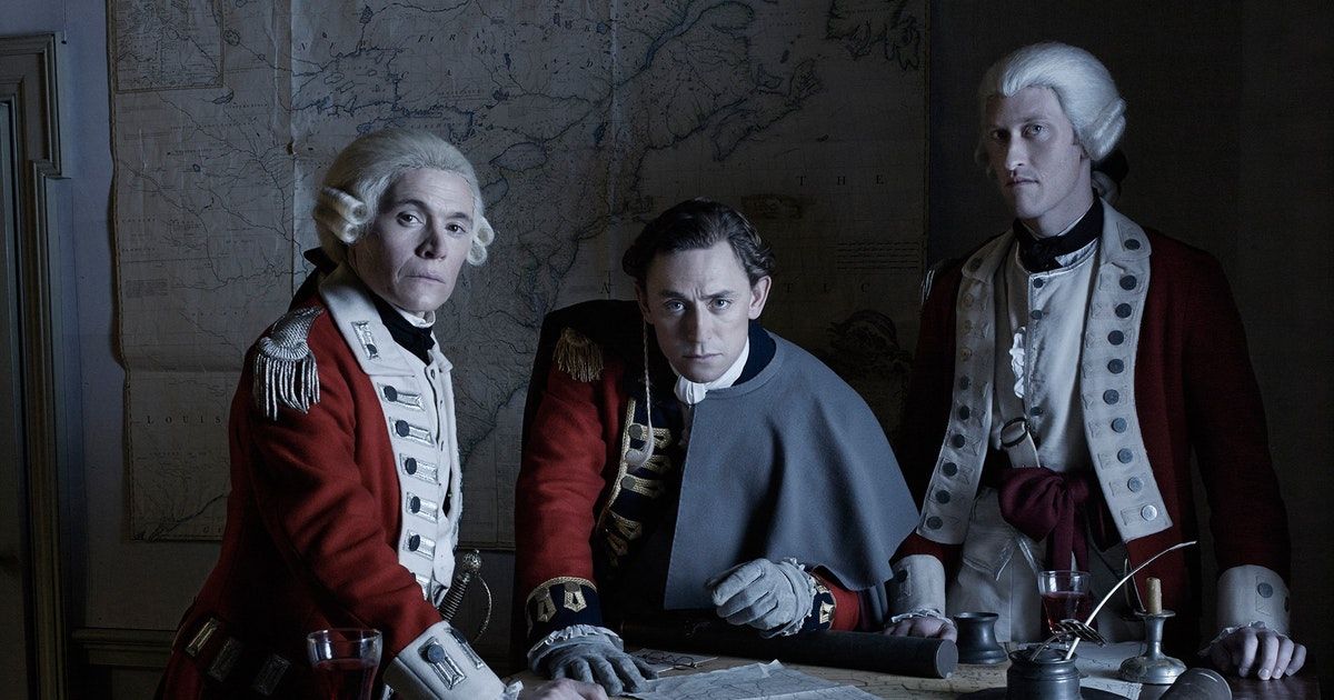 The suited cast of Turn: Washington's Spies stand at the table and look into the camera