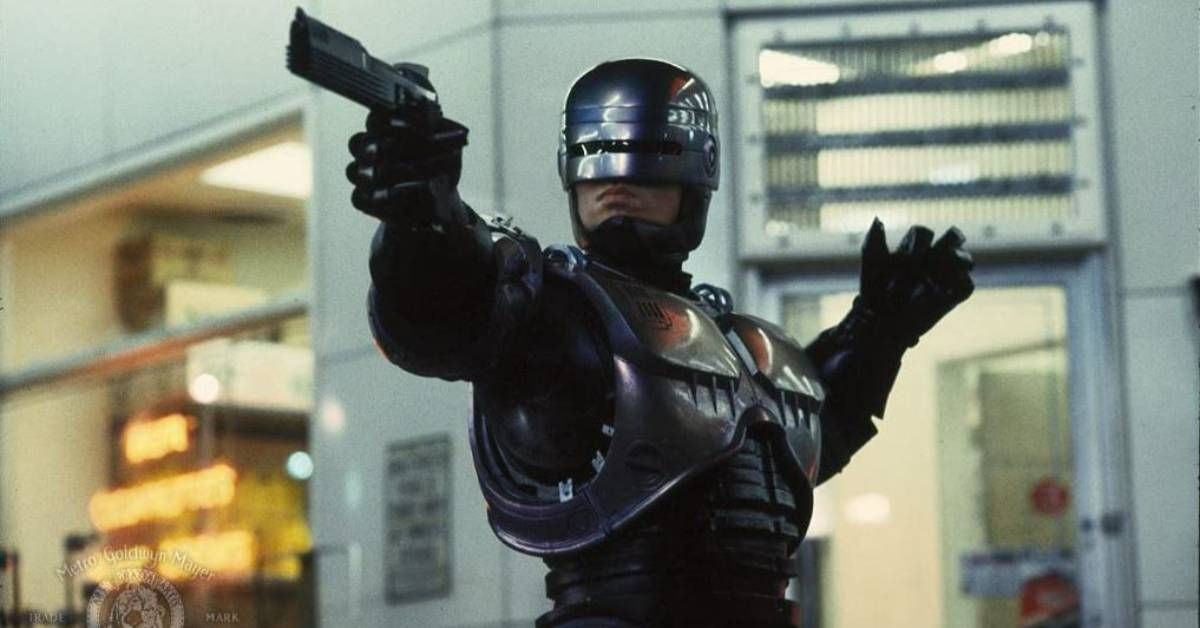 Peter Weller, no personagem de um policial andróide, segura uma arma durante uma cena de 