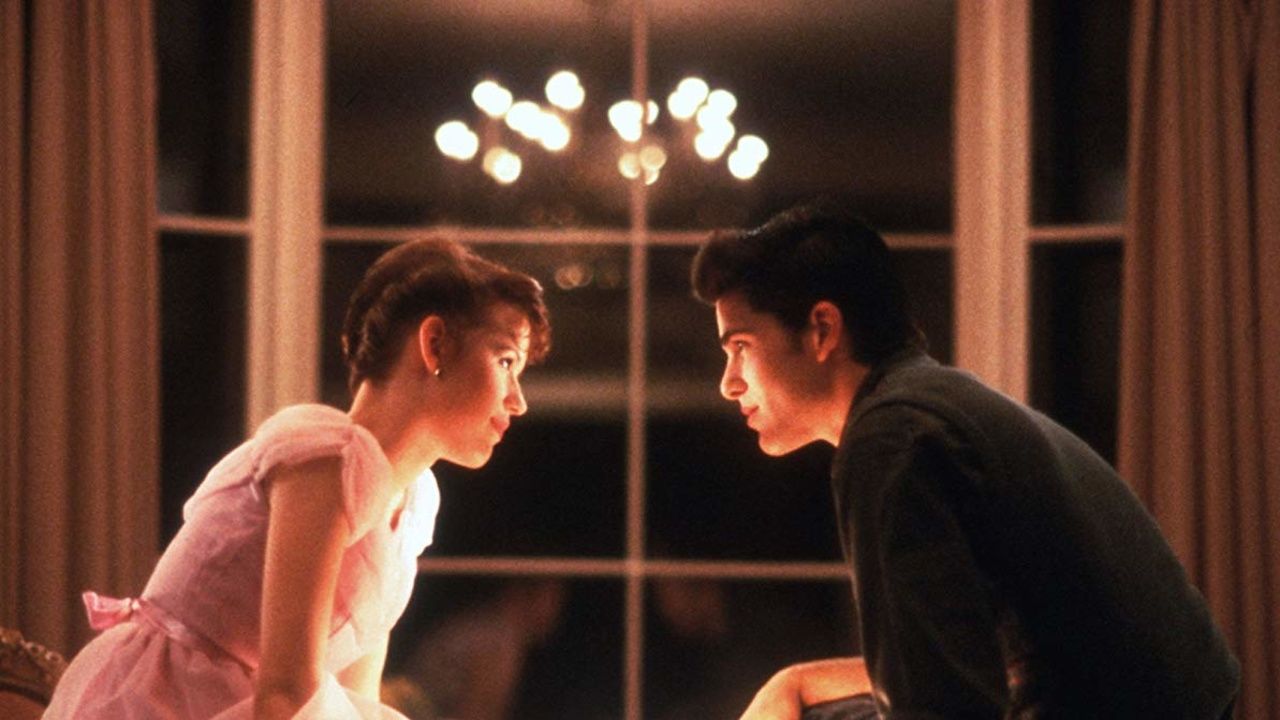 Molly Ringwald in a pink dress across from her date in Sixteen Candles