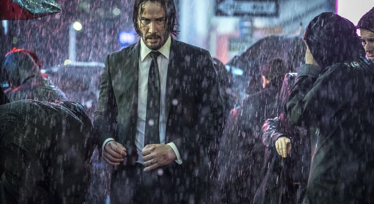 John Wick on a crowded street in the rain.