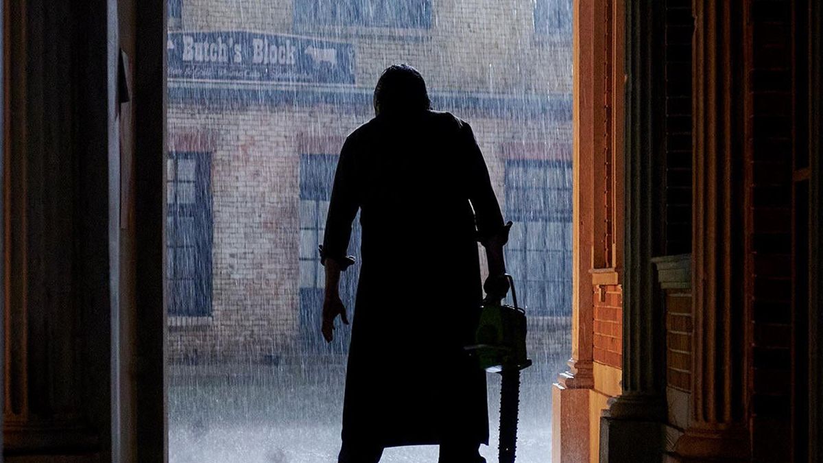 Leatherface's silhouette holding a chainsaw in the rain