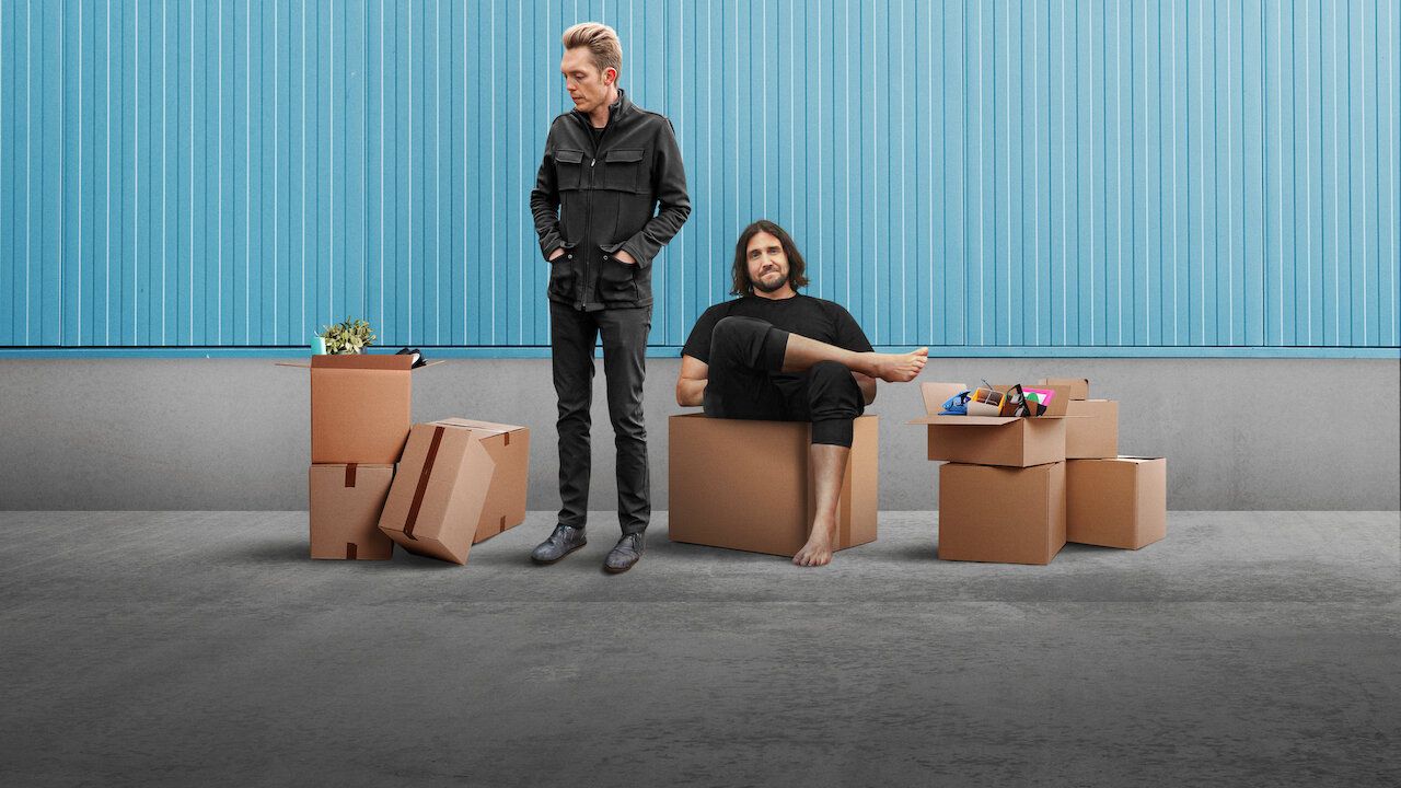The creators of minimalism stand and sit amongst cardboard boxes with a sparse blue backdrop