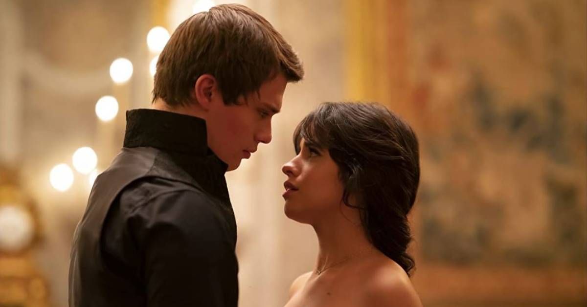 Nicholas Galitzine and Camila Cabello, in character as the Prince and Cinderella, stand together during an indoor scene from Cinderella (2021).