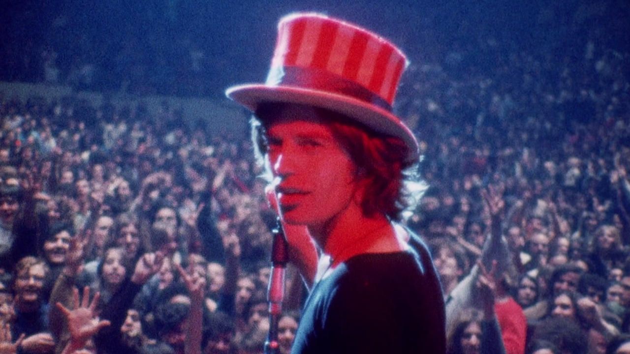 Mick Jagger wears an Uncle Sam hat and looks at the camera while on stage