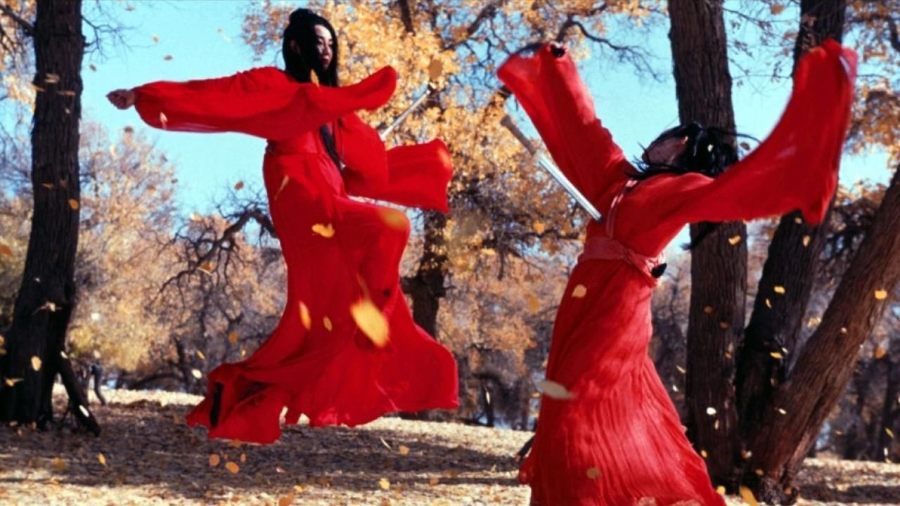 Maggie Cheung in flowing red fights someone else in red on a windy autumn day