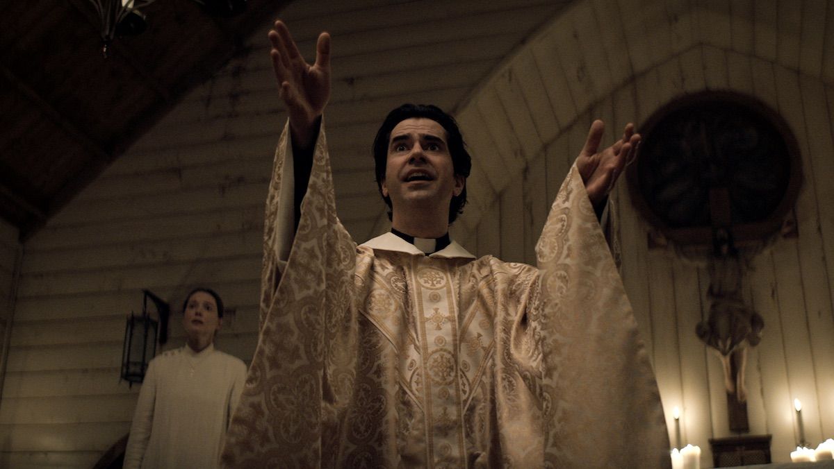Hamish Linklater stretches his arm out during a sermon in Midnight Mass.