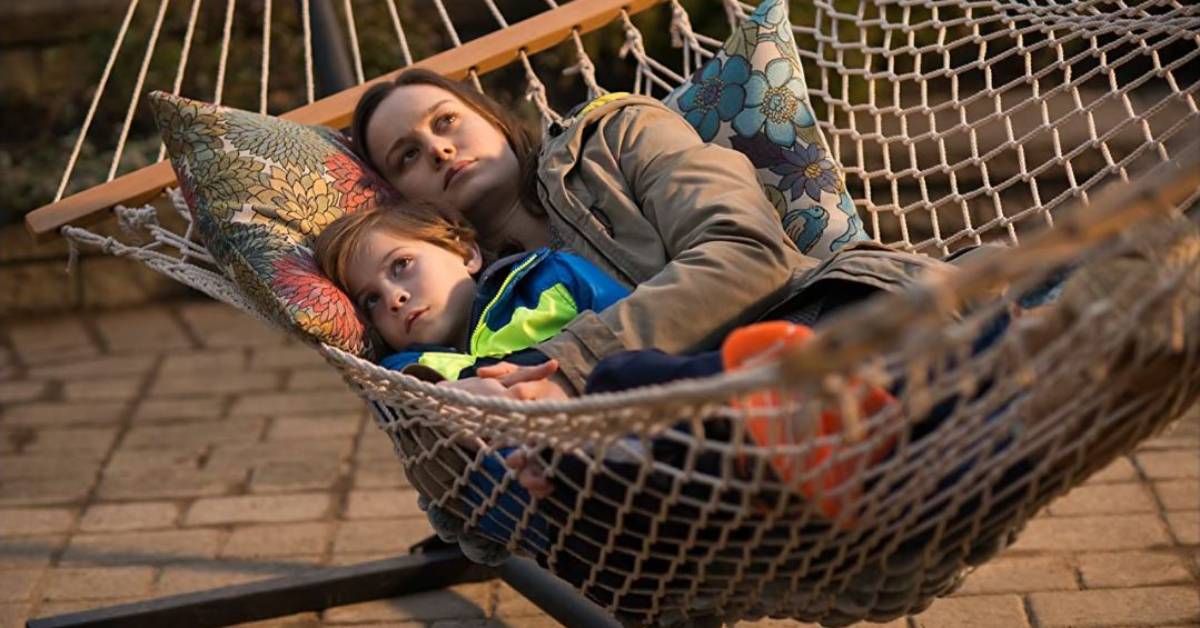 Jacob Tremblay and Brie Larson, in character as son and mother, lie together on a hammock during an outdoor scene from Room (2015).