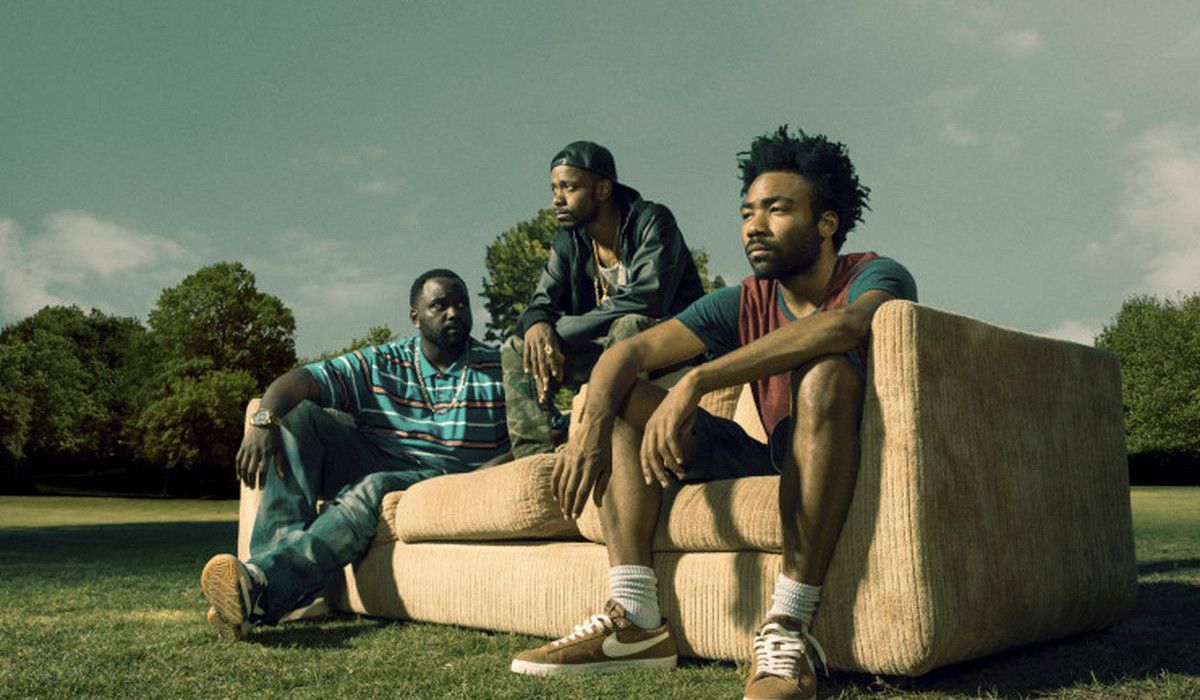 Brian Tyree Henry, LaKeith Stanfield and Donald Glover sitting on a couch on a field in Atlanta.