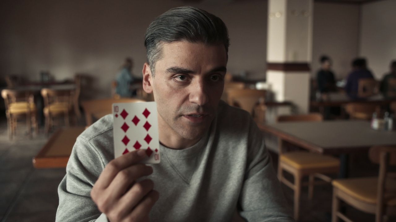 Oscar Isaac holding a playing card. 