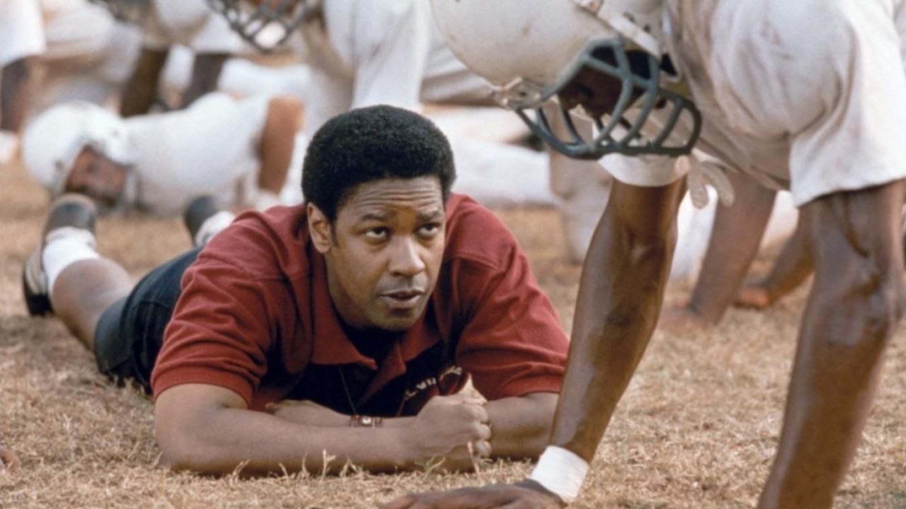 Denzel Washington lays on the ground, coaching his quarterback