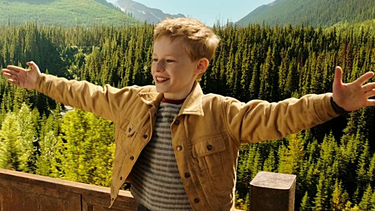 Kyle Catlett as T. S. Spivet with his arms spread wide, a large forest behind him.
