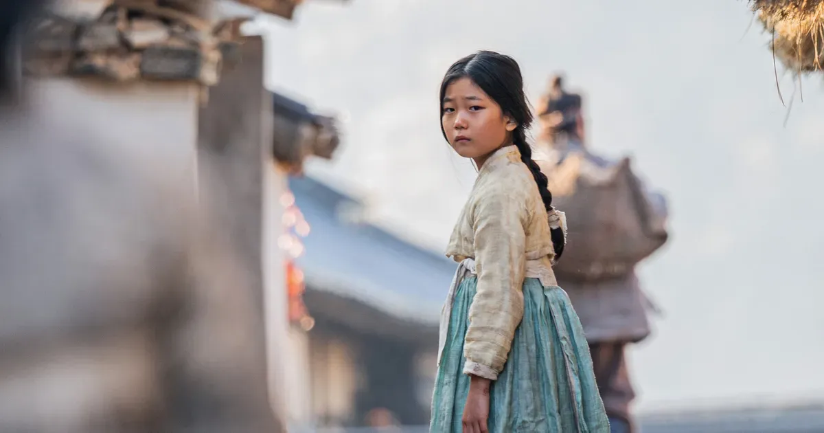 Girl in traditional Korean hanbok looks back.
