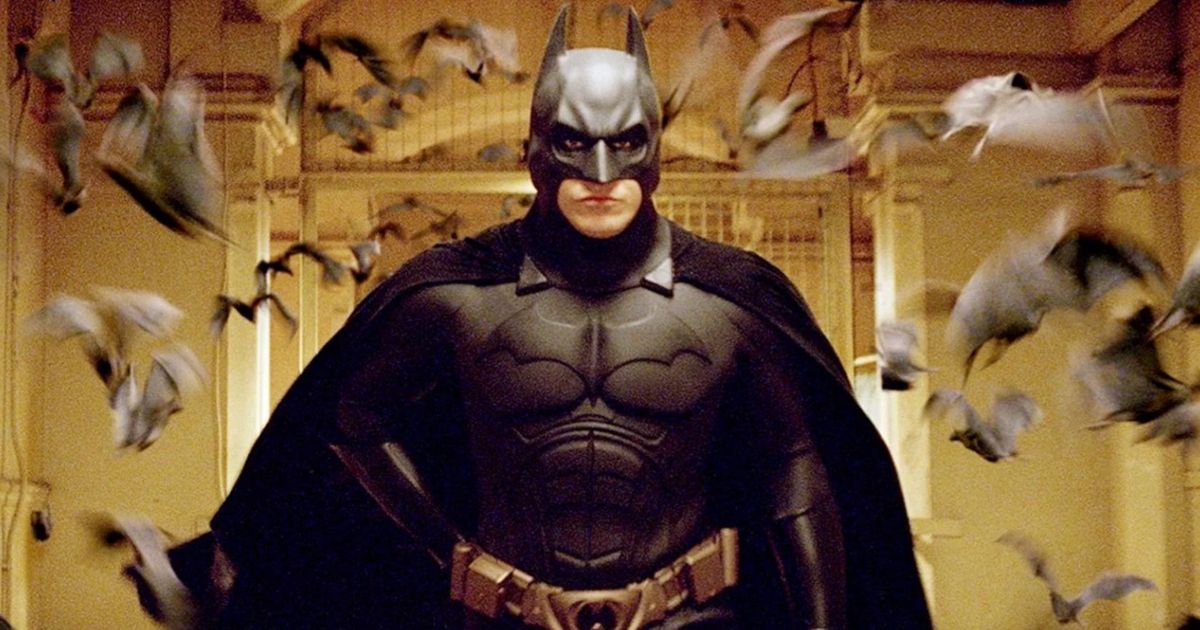 Batman stands in a room with birds flying around him in Batman Begins