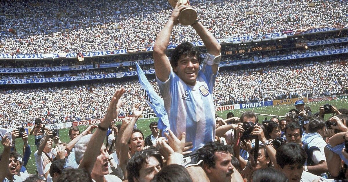 Diego Maradona holds a trophy surrounded by fans