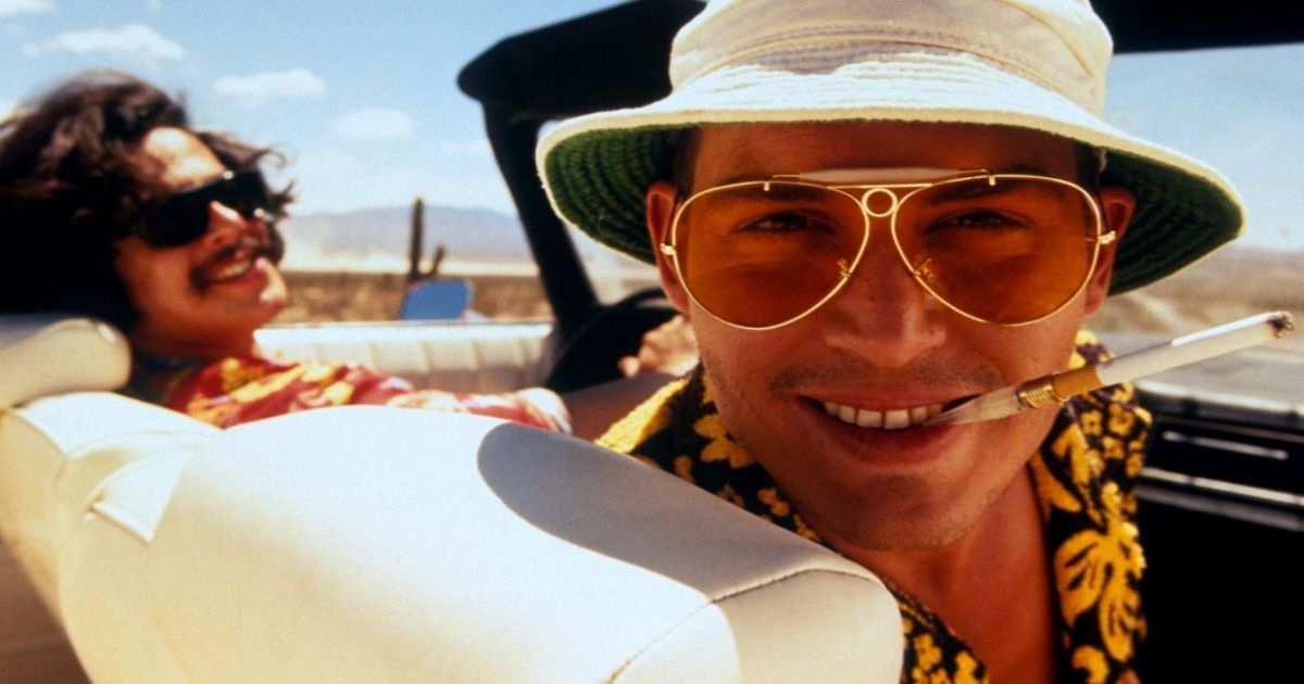Johnny Depp and Benicio Del Toro smoke and smile at the camera in Fear and Loathing