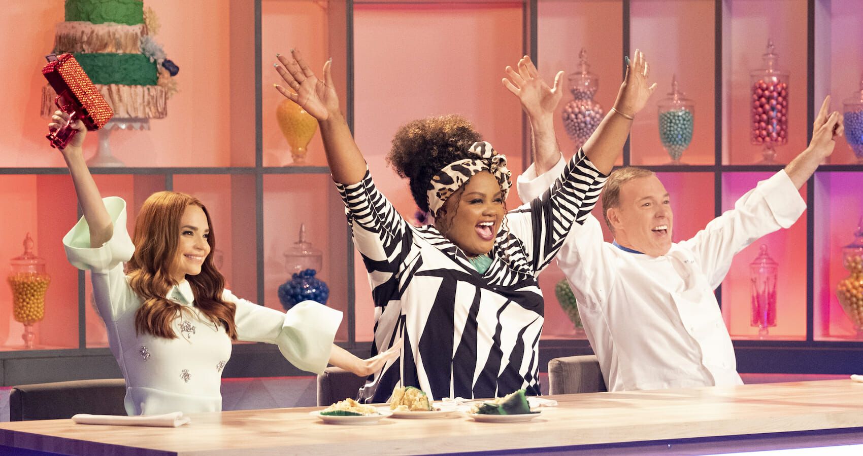 Nicole in the center and chefs to each side celebrate in Nailed It!