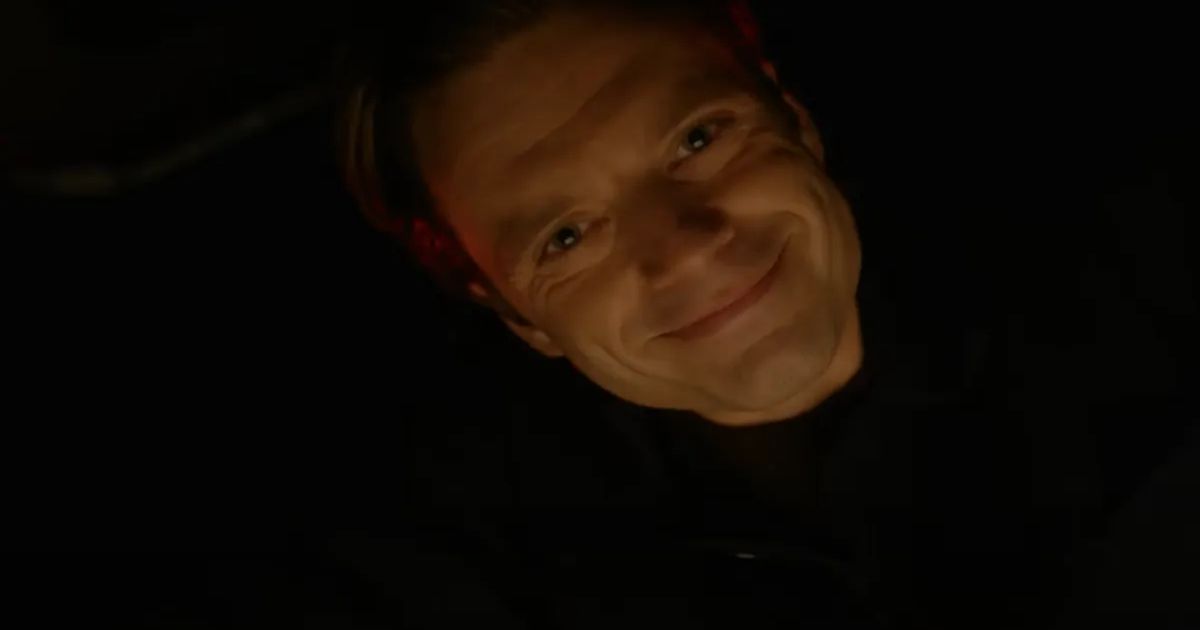 Sebastian Stan's face smiling in the darkness in Fresh
