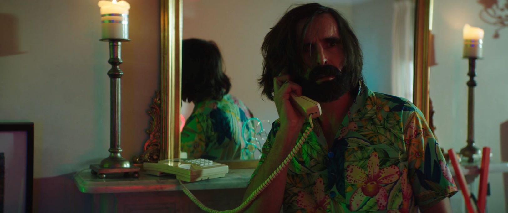 Joe Honson on the phone looks surprised in a hawaiian shirt