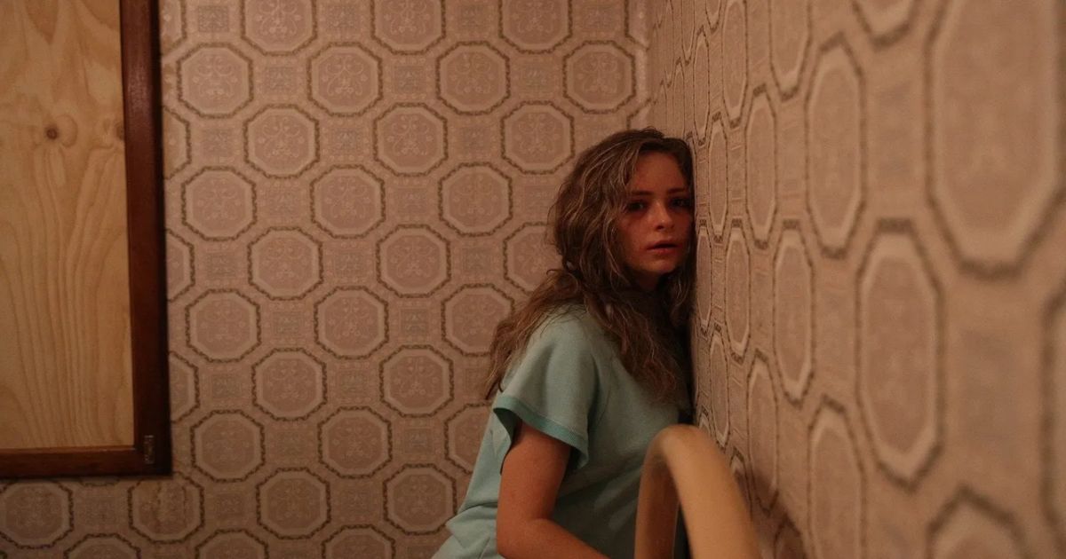 A woman clings to the wall in Hounds of Love