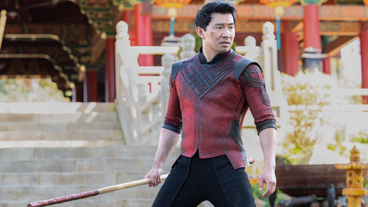 Simu Liu as Shang Chi holding a staff as if he is preparing for a fight.