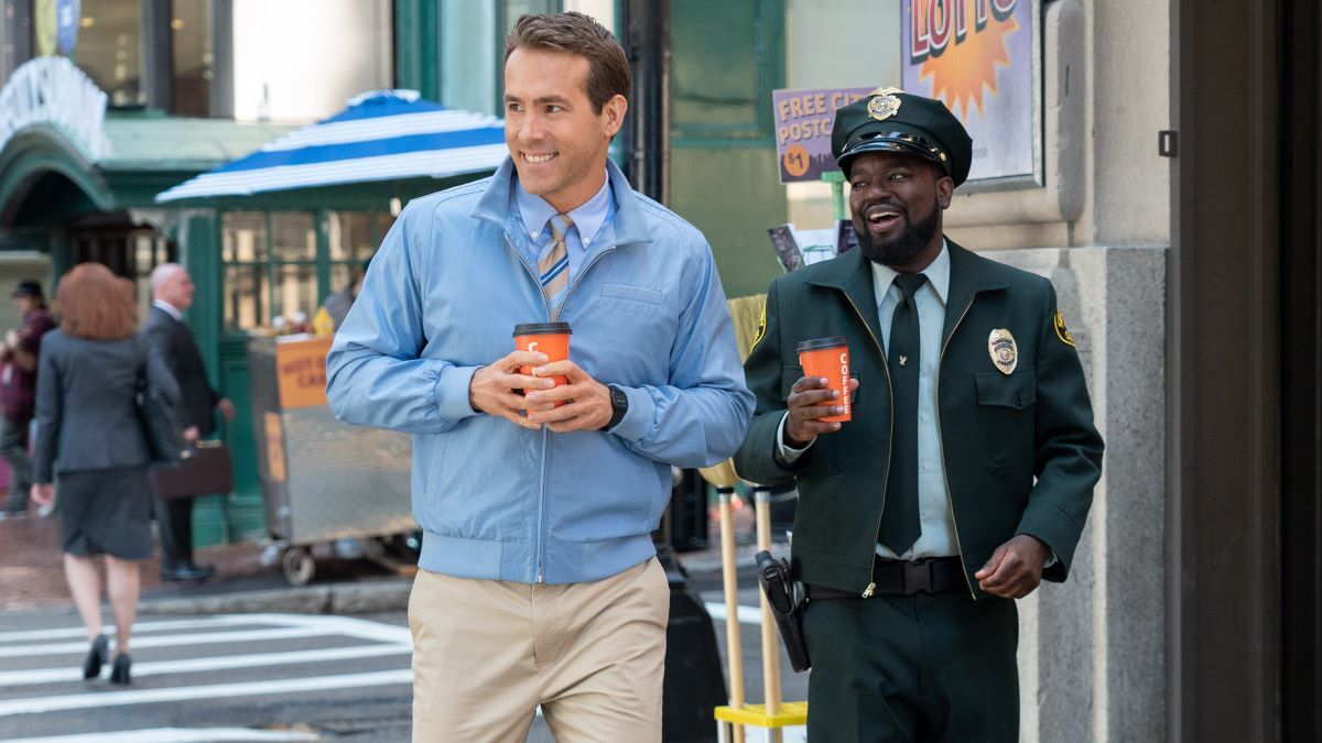 Ryan Reynolds and Lil Rel Howery in Free Guy, holding coffee and smiling.