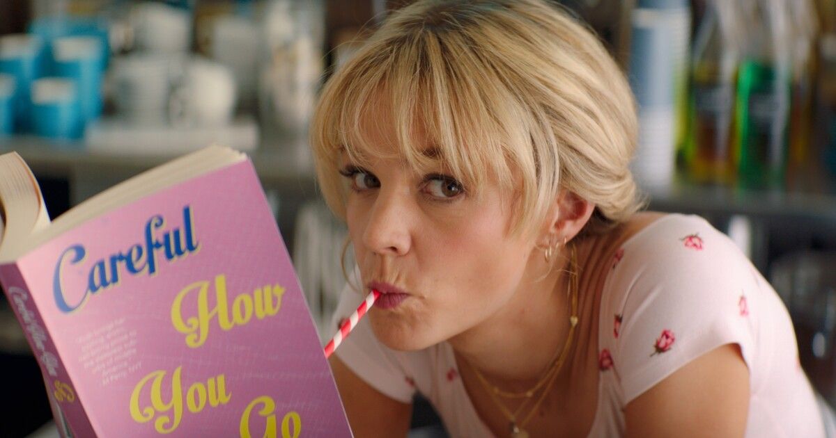 Mulligan reading a book and sucking a candy cane in Promising Young Woman