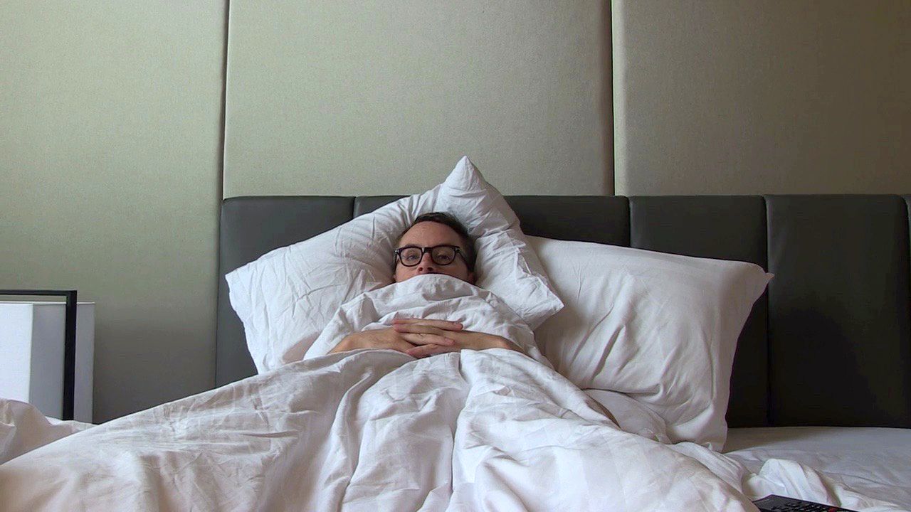 Nicolas Winding Refn in bed with the sheets pulled up to his head in the documentary My Life Directed by Nicolas Winding Refn