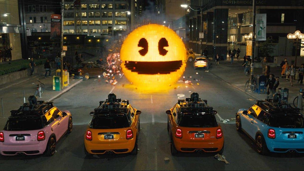 Pac-Man on a city street, facing four cars colored like the Pac-Man ghosts.