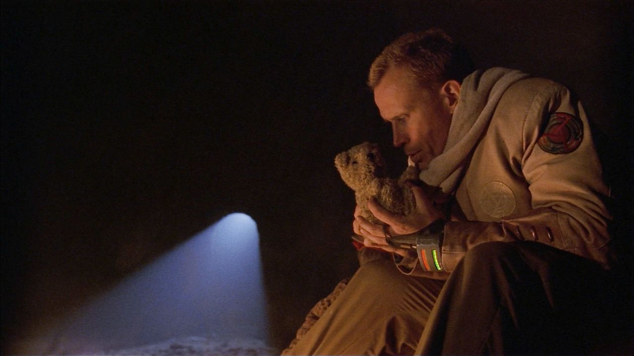 Peter Weller holds a teddy bear in a weird dumb scene from Screamers