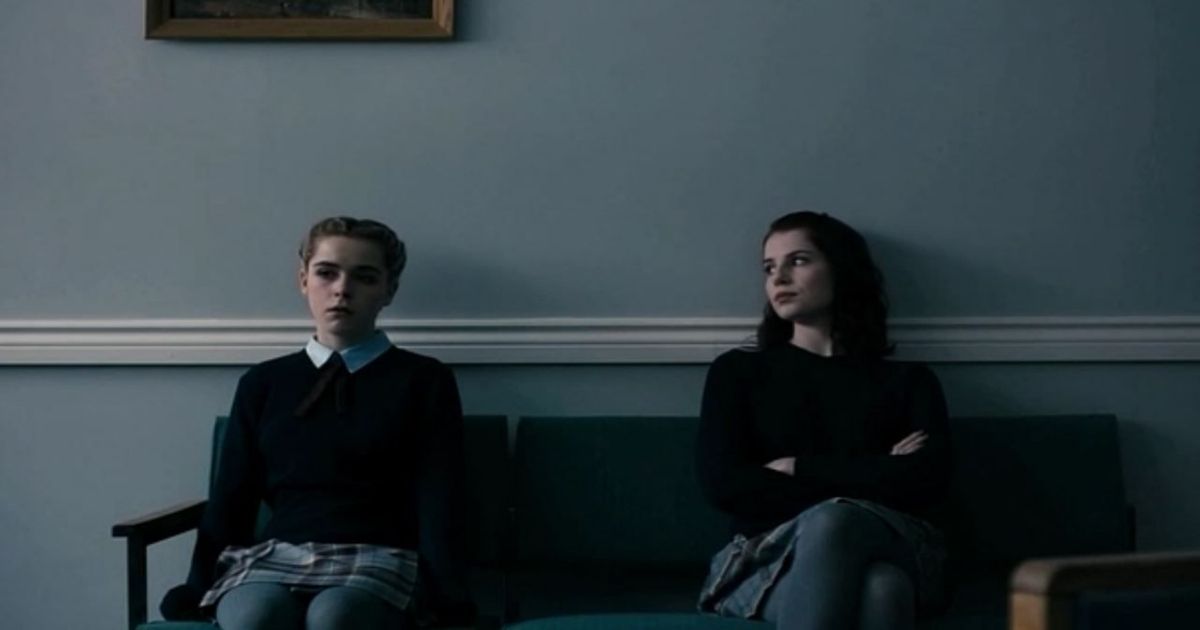 The girls sit apart from each other on a bench in The Blackcoat's Daughter