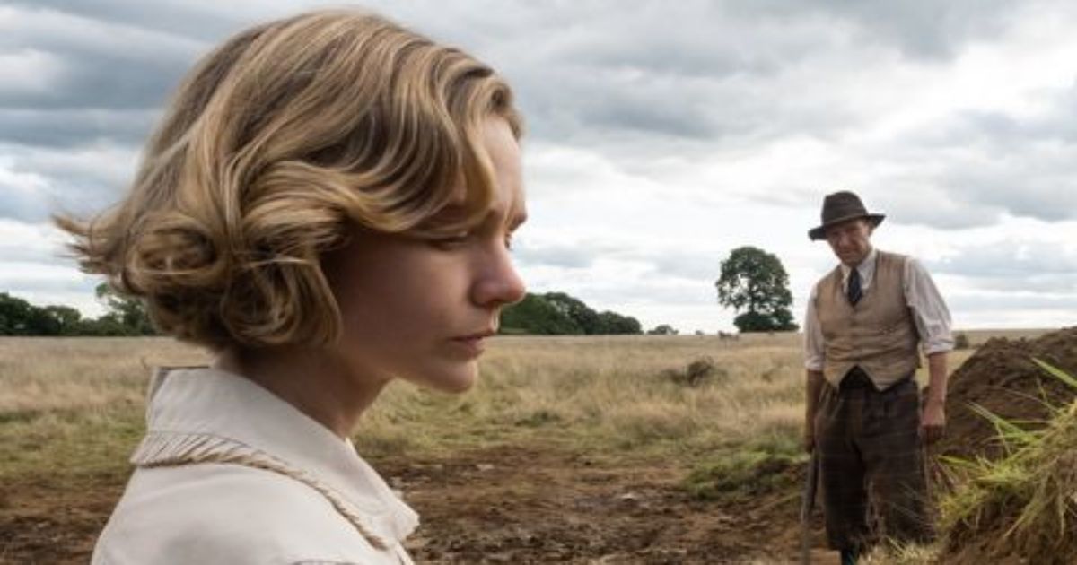 Carey Mulligan in the foreground and Ralph Fiennes in a field in The Dig