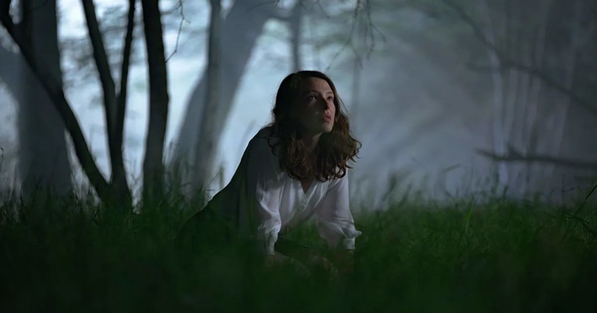 A woman in a white nightgown in the dark forest in The Feast