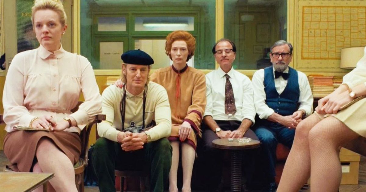 The cast sits in the newsroom in The French Dispatch