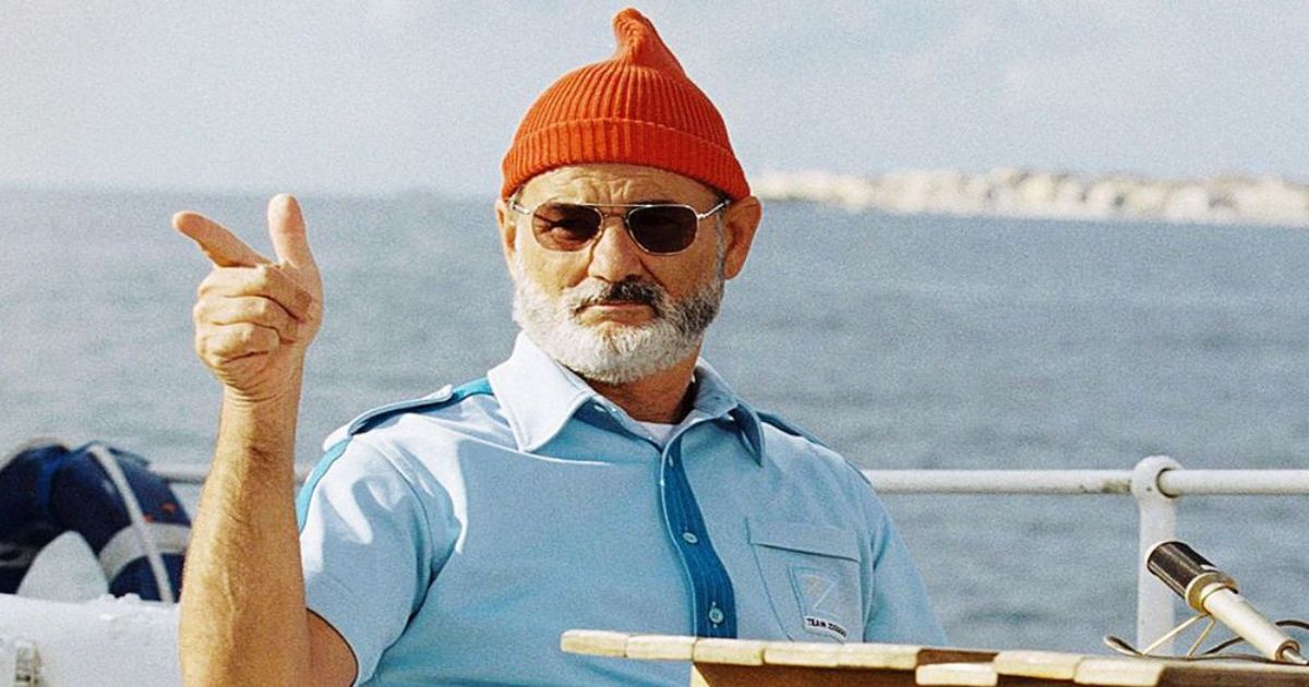 Bill Murray como Steve Zissou em um boné vermelho em um barco em The Life Aquatic