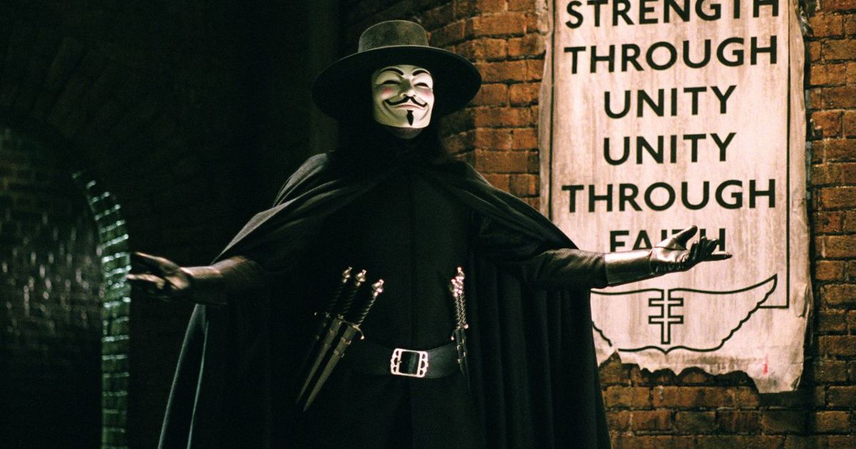 Hugo Weaving as V in front of a propaganda sign in V For Vendetta