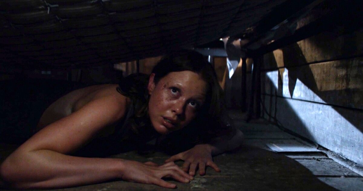 Mia Goth hides under a bed in X