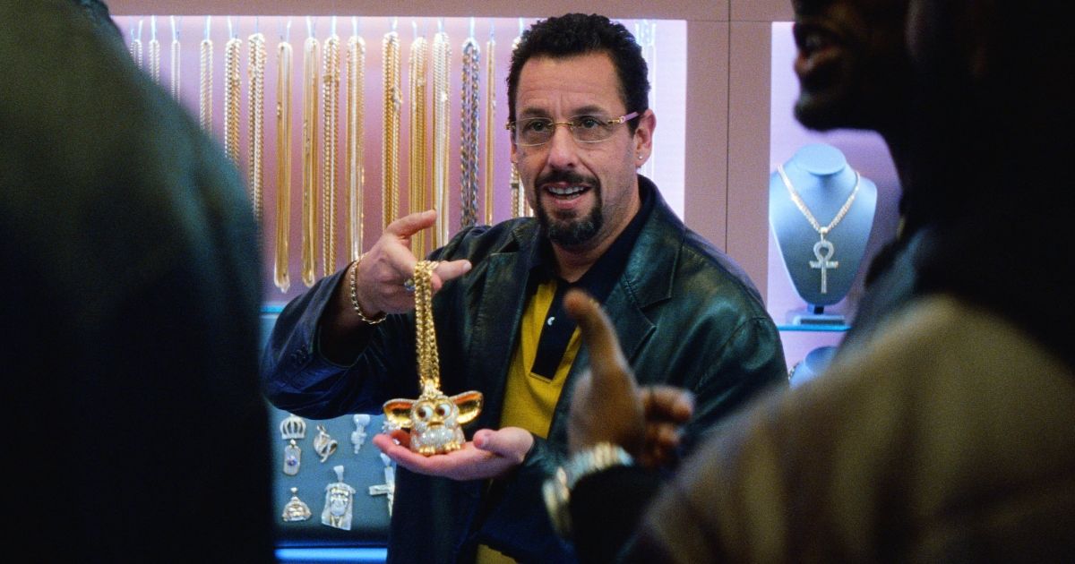 Adam Sandler holds jewelry in the stressful movie Uncut Gems