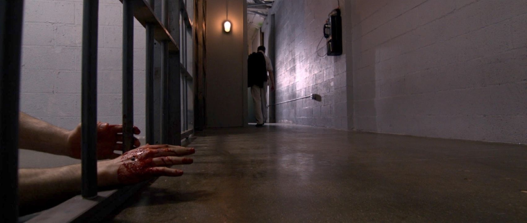 A bloody hand lays outside a prison cell in the hallway