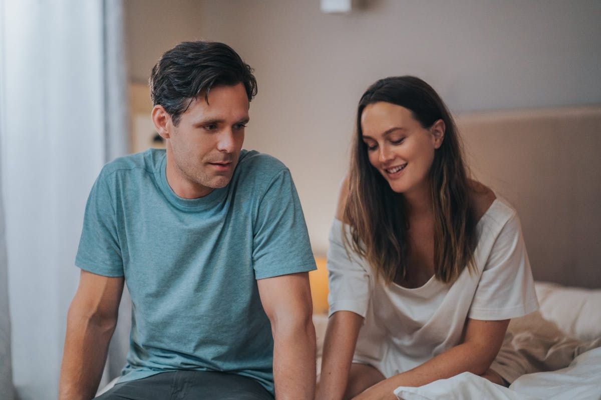 Man and woman sit in bed together.