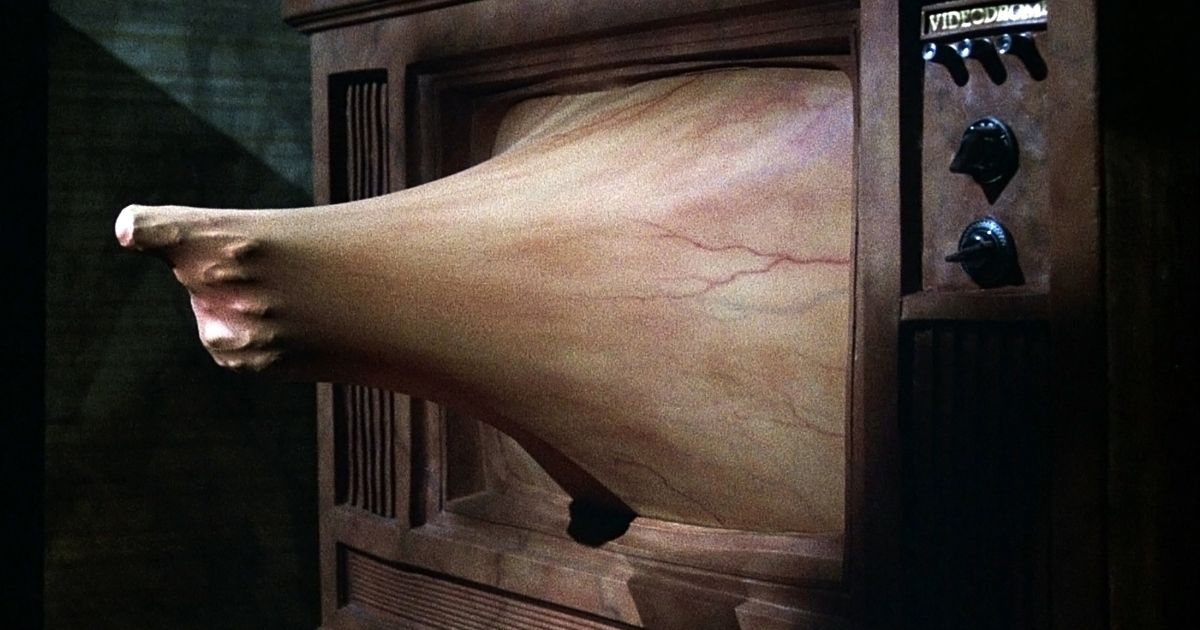 A fleshy hand with a gun pushes through a TV screen in Videodrome