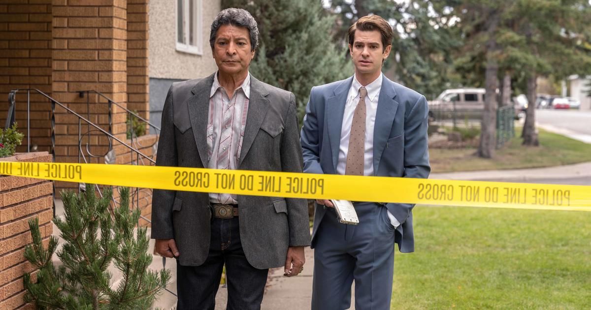 Two men stand in front of crime scene tape.