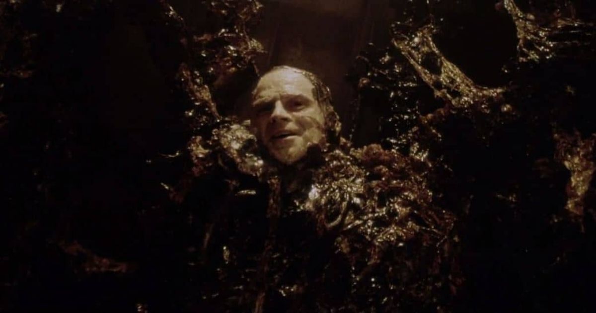 A man attached to the Xenomorph breeding wall in Alien Resurrection