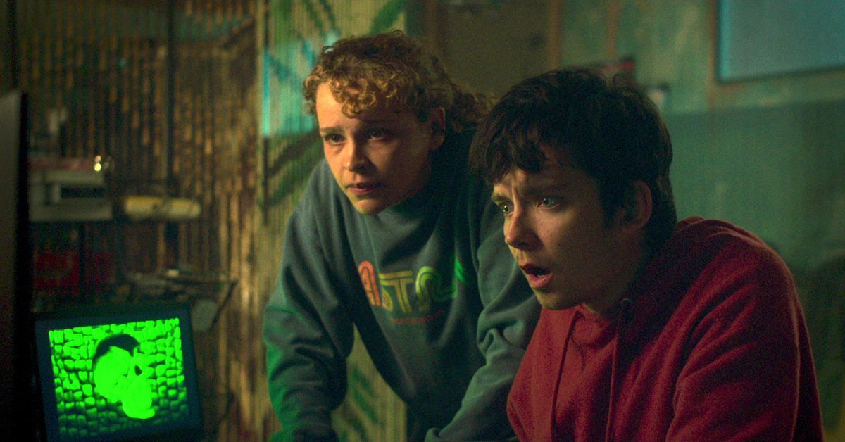 Asa Butterfield and Kayla look at a green skull on a computer in Choose or Die