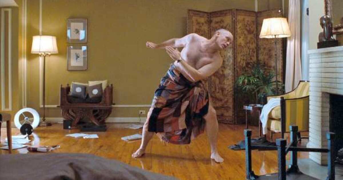 Malkovich dances shirtless in a bath towel in Being John Malkovich